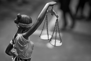Rear view of themis statue with balance scales in black and white